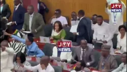 Majority MPs chanting, each holding a printed picture of Ken Ofori-Atta.