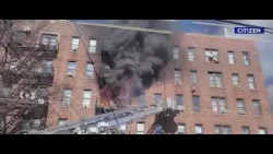 Человек машет рукой, призывая на помощь, в то время как в здании в Бронксе бушует пожар.